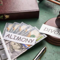 alimony and divorce signs on table with calculator dollar notes and gavel on desk