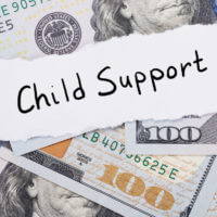 Child support note on top of hundred-dollar bills