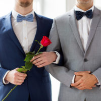 Two Men, one holding a rose